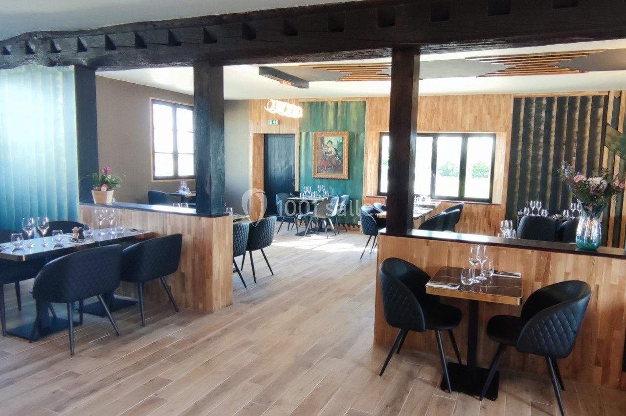 Salle de restaurant lumineuse avec tables en bois, chaises noires et décoration moderne en bois et verre.