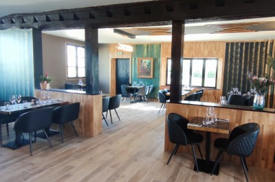 Salle de restaurant lumineuse avec tables en bois, chaises noires et décoration moderne en bois et verre.