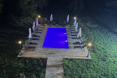 Chambre avec lits superposés en bois, poutres apparentes au plafond et sol en tomettes anciennes.