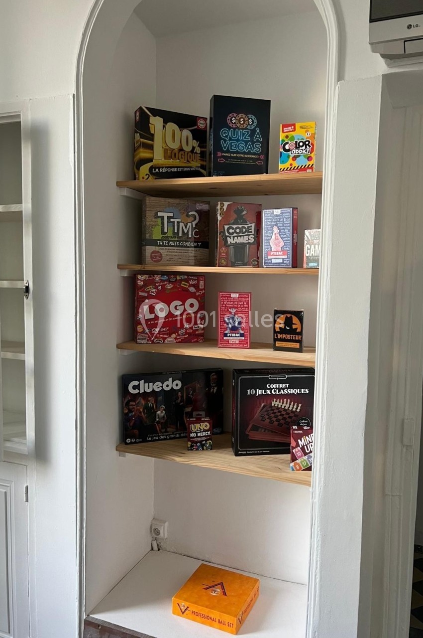 Étagères en bois dans une niche murale, garnies de boîtes de jeux de société variés.