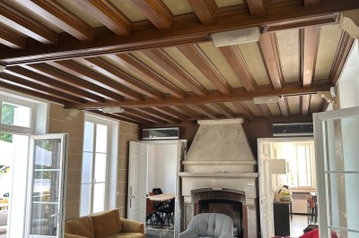 Chambre avec lits superposés en bois, poutres apparentes au plafond et sol en tomettes anciennes.