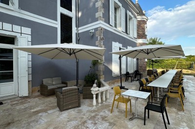 Chambre avec lits superposés en bois, poutres apparentes au plafond et sol en tomettes anciennes.