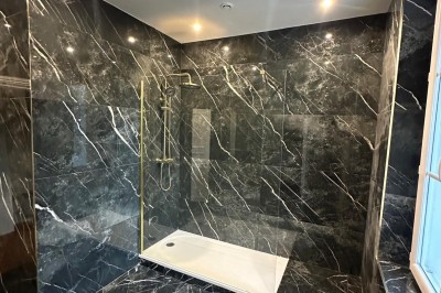 Chambre avec lits superposés en bois, poutres apparentes au plafond et sol en tomettes anciennes.