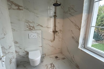 Chambre avec lits superposés en bois, poutres apparentes au plafond et sol en tomettes anciennes.