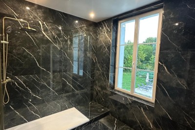 Chambre avec lits superposés en bois, poutres apparentes au plafond et sol en tomettes anciennes.