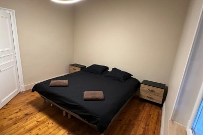 Chambre avec lits superposés en bois, poutres apparentes au plafond et sol en tomettes anciennes.