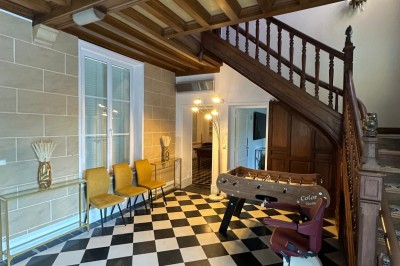 Chambre avec lits superposés en bois, poutres apparentes au plafond et sol en tomettes anciennes.