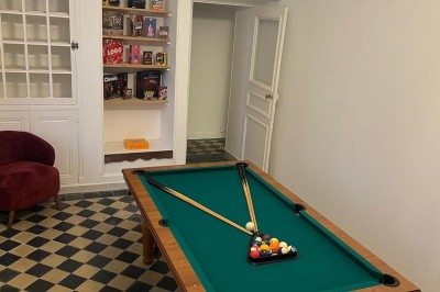 Chambre avec lits superposés en bois, poutres apparentes au plafond et sol en tomettes anciennes.