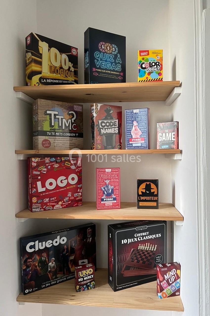 Étagères en bois contenant divers jeux de société colorés, organisés sur plusieurs niveaux.