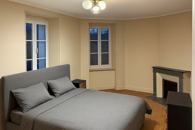 Chambre avec lits superposés en bois, poutres apparentes au plafond et sol en tomettes anciennes.