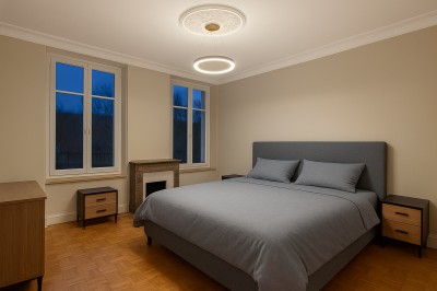 Chambre avec lits superposés en bois, poutres apparentes au plafond et sol en tomettes anciennes.