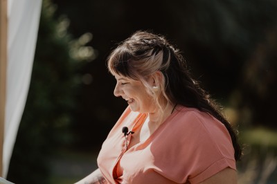 Un couple allume ensemble une bougie blanche lors d'une cérémonie, entouré de fleurs et de verdure.