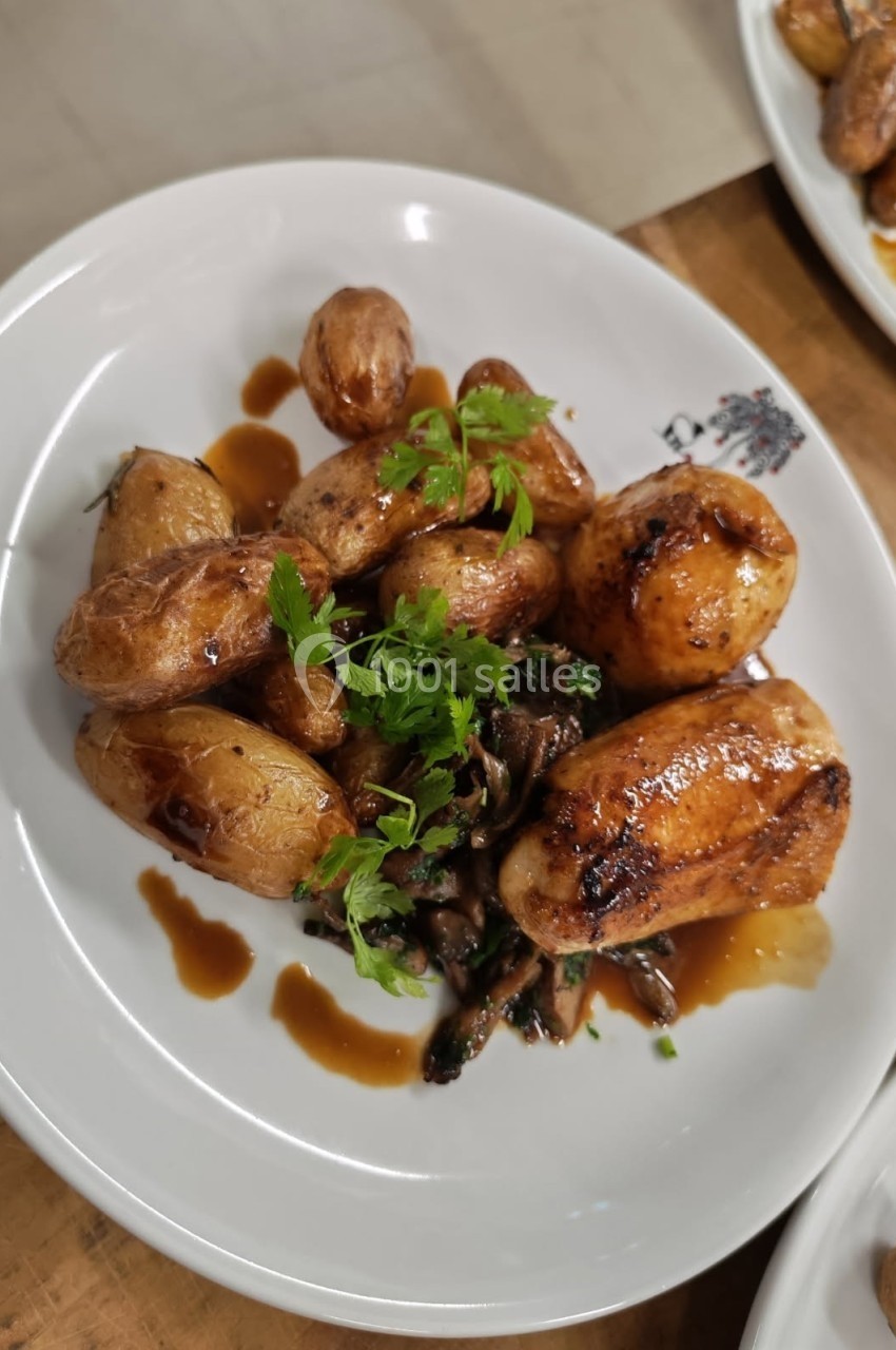Assiette de pommes de terre rôties, champignons et viande nappés de sauce, garnie de persil frais.