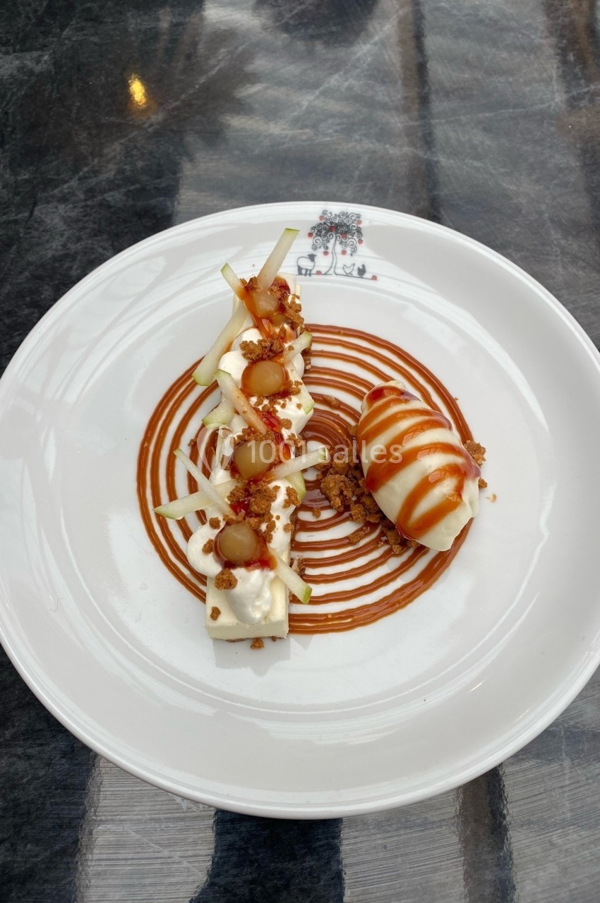 Assiette de dessert composée de mousse, pommes, caramel et crumble, présentée avec soin sur une table sombre.