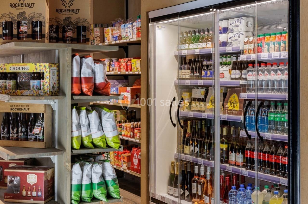 Rayons d'une épicerie avec boissons réfrigérées, produits alimentaires emballés et étagères de bières artisanales.