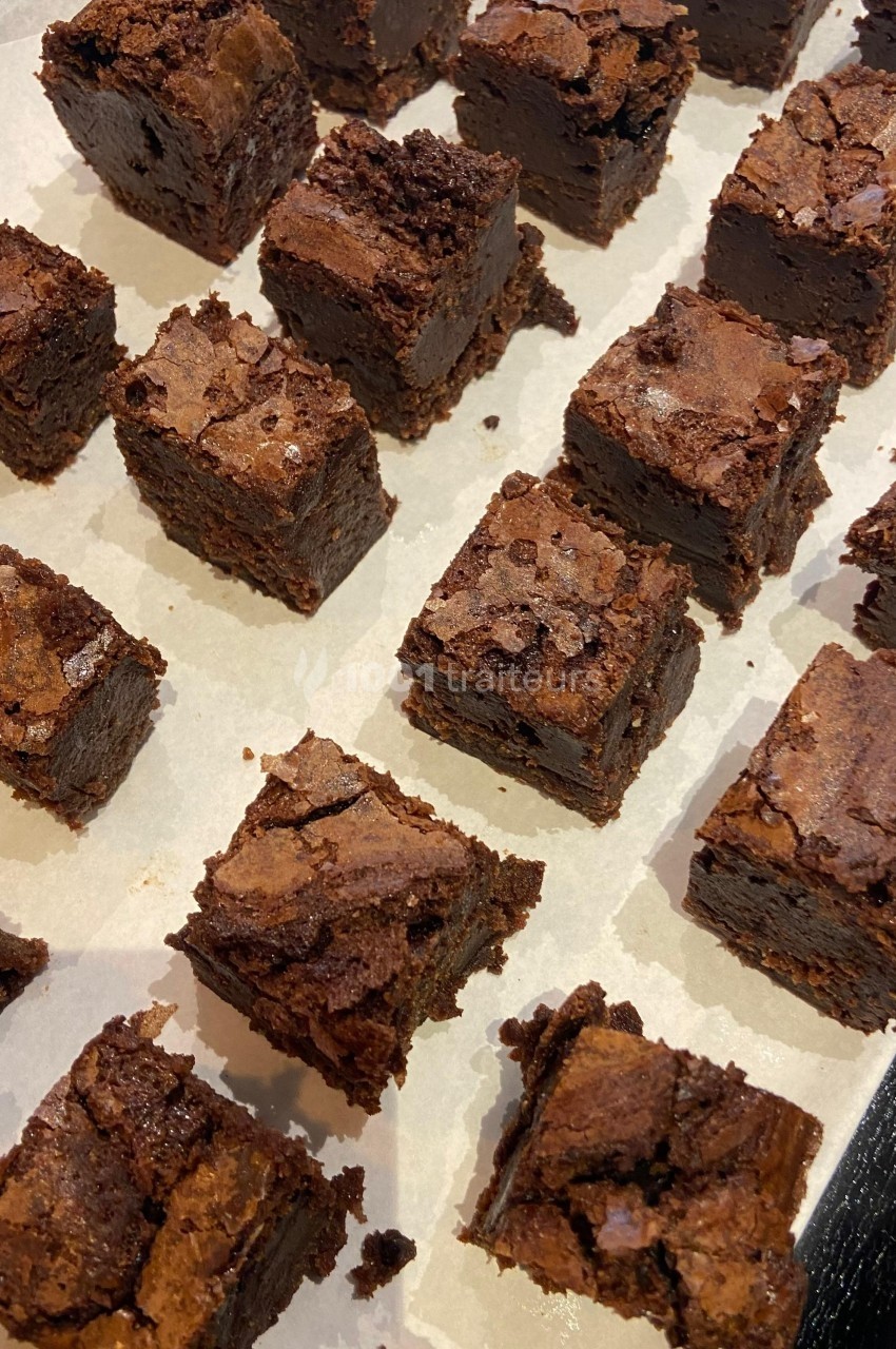Carrés de brownie au chocolat disposés sur du papier sulfurisé.
