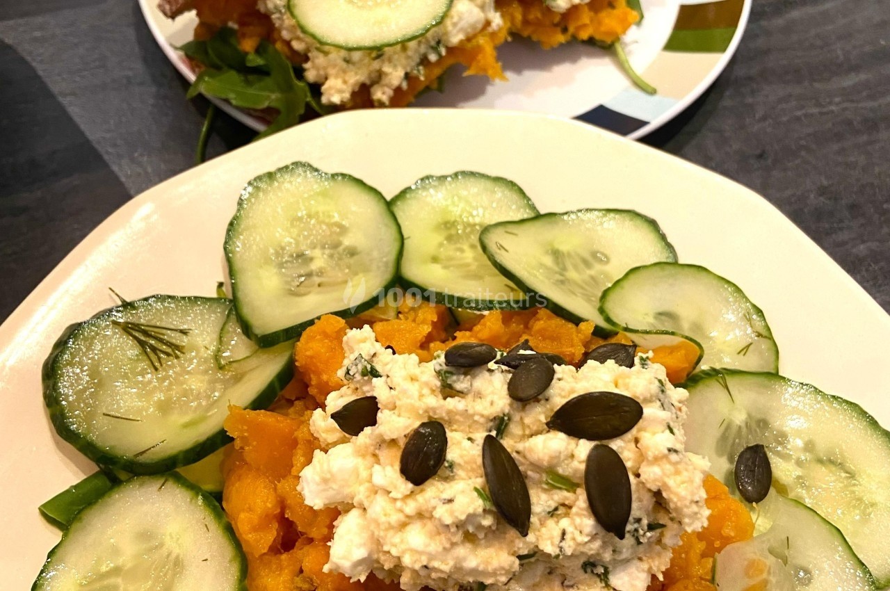 Assiette garnie de purée de patate douce, tranches de concombre, graines de courge et fromage frais.