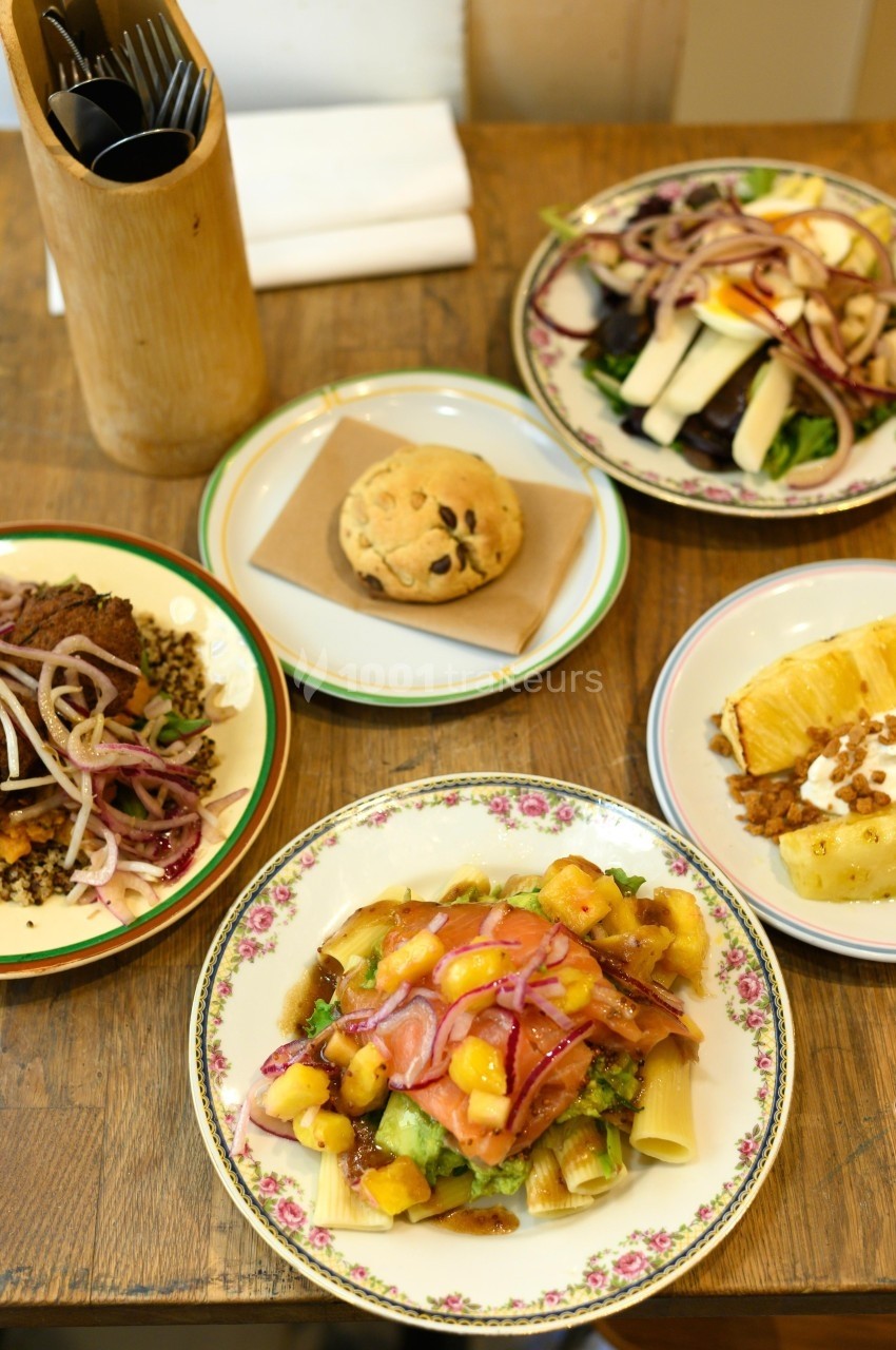 Assortiment de plats servis sur une table en bois, comprenant des salades, un gratin et un petit pain.