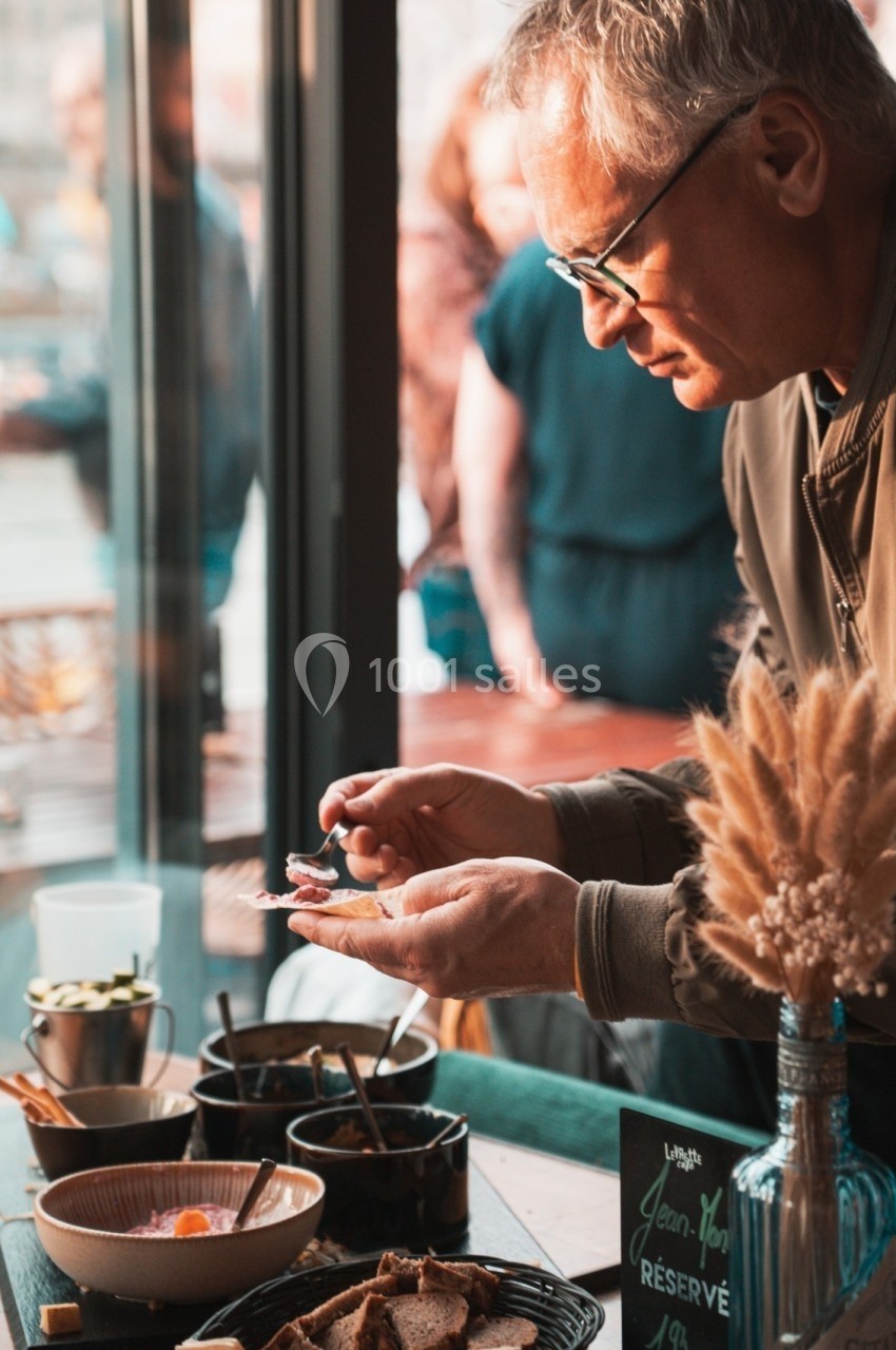 Un homme prépare un plat avec soin dans un cadre lumineux, entouré de bols et d'ingrédients sur une table.