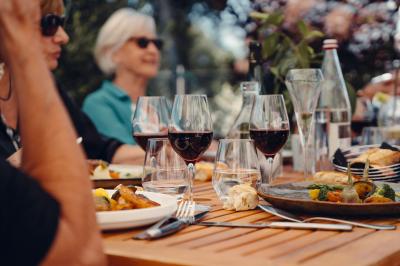 Trois femmes souriantes lisent des magazines allongées sur un lit dans une chambre lumineuse.