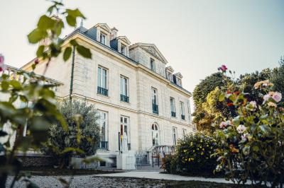 Trois femmes souriantes lisent des magazines allongées sur un lit dans une chambre lumineuse.