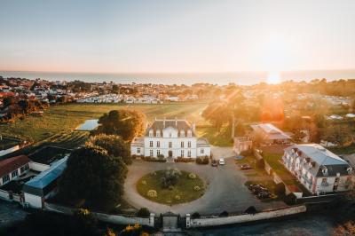 Trois femmes souriantes lisent des magazines allongées sur un lit dans une chambre lumineuse.