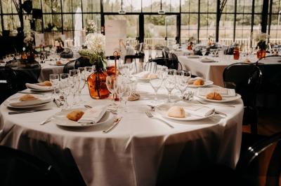 Trois femmes souriantes lisent des magazines allongées sur un lit dans une chambre lumineuse.