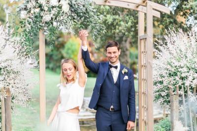 Trois femmes souriantes lisent des magazines allongées sur un lit dans une chambre lumineuse.