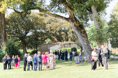 Trois femmes souriantes lisent des magazines allongées sur un lit dans une chambre lumineuse.