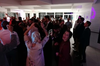 Groupe de personnes dansant et célébrant dans une salle éclairée, ambiance festive en soirée.