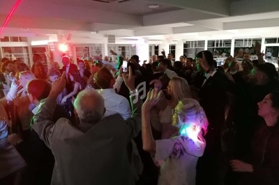 Personnes dansant dans une salle éclairée par des lumières colorées, ambiance festive en soirée.