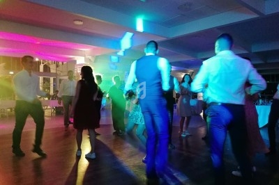 Personnes dansant dans une salle éclairée par des lumières colorées, ambiance festive en soirée.