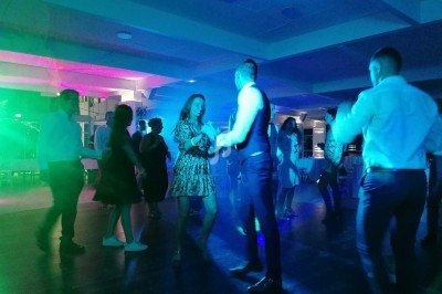 Personnes dansant dans une salle éclairée par des lumières colorées, ambiance festive en soirée.