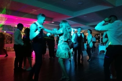 Personnes dansant dans une salle éclairée par des lumières colorées, ambiance festive en soirée.