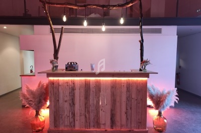 Comptoir en bois décoré de pampas et éclairé par des ampoules suspendues, dans un espace intérieur moderne.