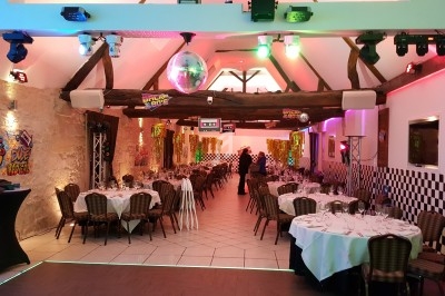 Salle décorée sur le thème des années 80 avec tables dressées, éclairages colorés et éléments rétro.