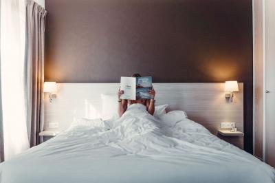 Un homme verse du vin dans une carafe en verre, en extérieur, avec des plantes floues en arrière-plan.