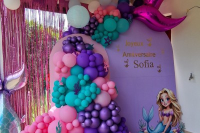 Miniature La Magie des Ballons #4 Arc décoratif en ballons roses, bleus et dorés avec papillons, installé dans une pièce au sol en bois.