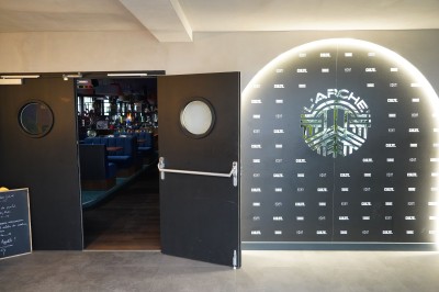 Toilettes roses décorées de mosaïques, affiches rétro sur les murs et miroir éclairé par des ampoules.