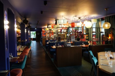 Toilettes roses décorées de mosaïques, affiches rétro sur les murs et miroir éclairé par des ampoules.