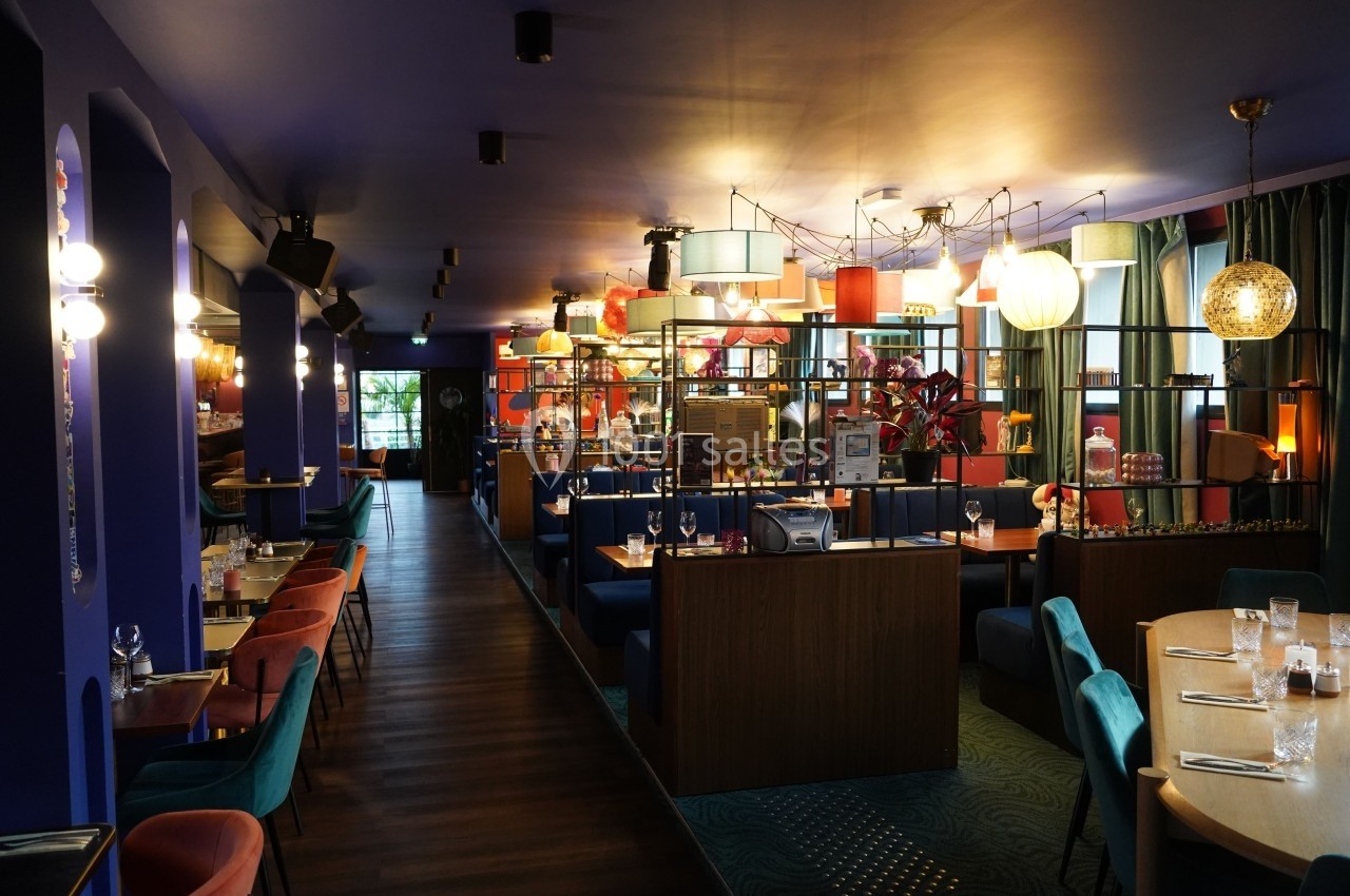 Salle de restaurant colorée avec mobilier moderne, éclairage chaleureux et décoration éclectique.