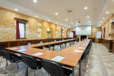 Table en bois dressée avec des verres, des couverts et des serviettes blanches, en extérieur avec un fond de verdure.