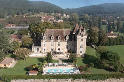 Table en bois dressée avec des verres, des couverts et des serviettes blanches, en extérieur avec un fond de verdure.