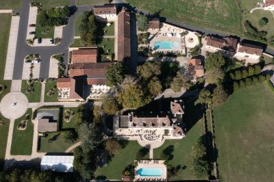 Table en bois dressée avec des verres, des couverts et des serviettes blanches, en extérieur avec un fond de verdure.