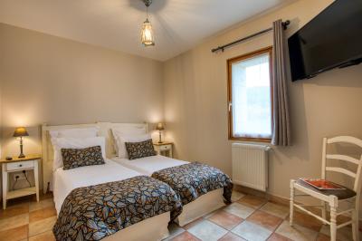 Table en bois dressée avec des verres, des couverts et des serviettes blanches, en extérieur avec un fond de verdure.