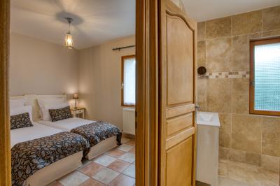 Table en bois dressée avec des verres, des couverts et des serviettes blanches, en extérieur avec un fond de verdure.