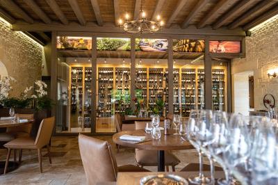 Table en bois dressée avec des verres, des couverts et des serviettes blanches, en extérieur avec un fond de verdure.