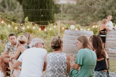 Miniature Location salle La Londe-les-Maures (Var) - Château Tour Saint Honoré #7 Un homme tenant un seau transparent rempli de bouteilles de vin rosé, en extérieur avec un fond flou de verdure.