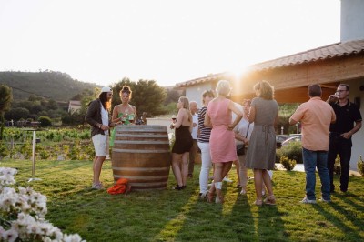 Miniature Location salle La Londe-les-Maures (Var) - Château Tour Saint Honoré #10 Un homme tenant un seau transparent rempli de bouteilles de vin rosé, en extérieur avec un fond flou de verdure.