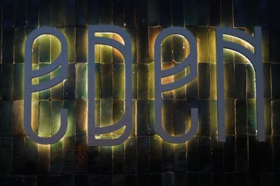 Bar moderne avec éclairage bleu, étagères remplies de bouteilles et ambiance tamisée.